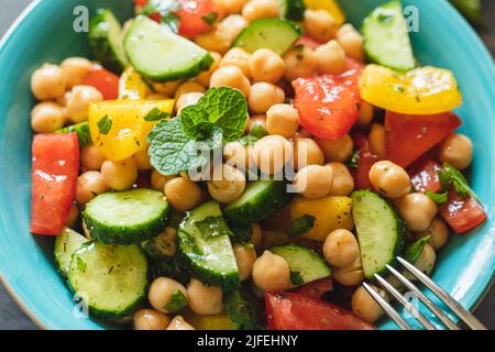 Insalata di ceci con pomodori, cetrioli, prezzemolo, cipolle in un piatto, fuoco selettivo. Cibo vegetariano sano, cucina orientale e mediterranea. Chic Foto Stock