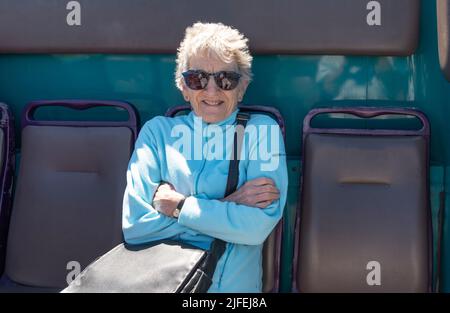 Cornovaglia, Inghilterra, Regno Unito. 2022. Villeggiante che viaggia sul ponte superiore di un autobus di servizio pubblico sorridendo e utilizzando un pass per l'autobus dei pensionati. Cornwall, Regno Unito Foto Stock