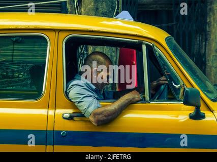 Kolkata, India - 26 giugno 2022: Un uomo seduto all'interno dell'iconico taxi giallo di Kolkata con un'espressione delusa. Messa a fuoco selettiva. Foto Stock