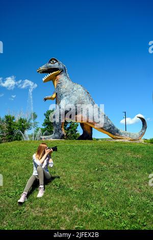 Donna turistica che scatta foto di Thyra l'enorme statua di dinosauro in Drumheller, la capitale del dinosauro del mondo, Alberta, Canada Foto Stock