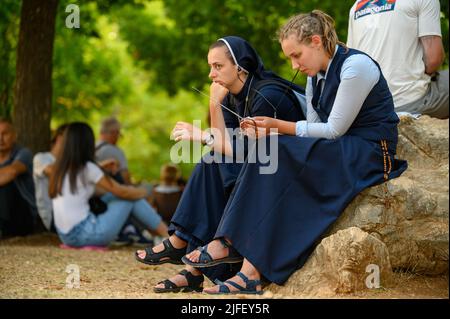 Due giovani monache, tra gli altri pellegrini, ascoltano una catechesi durante il Mladifest 2021 – la festa della gioventù – a Medjugorje. Foto Stock