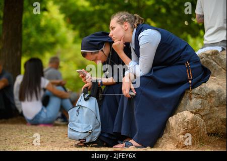 Due giovani monache, tra gli altri pellegrini, ascoltano una catechesi durante il Mladifest 2021 – la festa della gioventù – a Medjugorje. Foto Stock