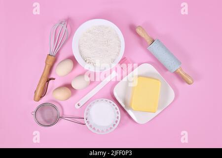 Gli ingredienti della pasta per torte e gli strumenti da forno su sfondo rosa Foto Stock