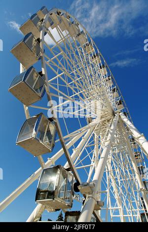 Ruota panoramica contro il cielo blu. Moderna ruota in ferro bianca. Vista dal basso Foto Stock