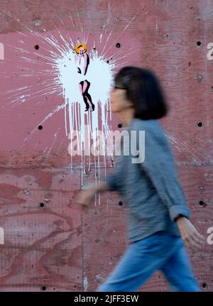 Una donna cammina accanto all'arte di strada su un muro del New Mexico raffigurando Marilyn Monroe in una famosa scena del film "The Seven Year itch". Foto Stock