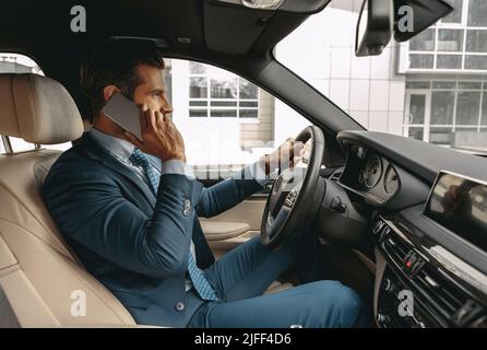 Vita su lato ritratto di vista del bel maschio caucasico che ha viaggio d'affari in auto mentre parla sul telefono cellulare Foto Stock