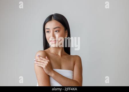 Giovane donna asiatica con pelle perfetta che tocca le spalle Foto Stock