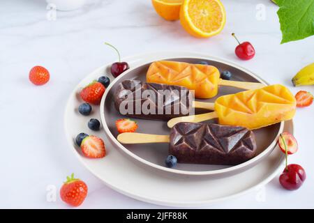 Popsicle autofarizzato con pezzi di frutta su sfondo marmoreo. Foto Stock