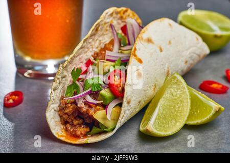 taco giallo con fettine di lime su tavola di pietra grigia Foto Stock