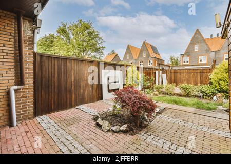 Cortile pulito di una casa moderna, con piastrelle giardino, prato, arbusti e alberi Foto Stock