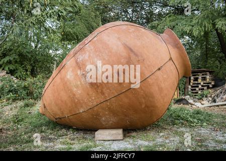 Grande kvevri in giardino di fronte ad un muro di pietra, Georgia Foto Stock