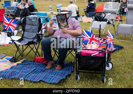 Woodstock, Oxfordshire, Regno Unito. 2nd luglio 2022. Programma di lettura uomo seduto per i proms di battaglia con trolly e Untion Jacks. Concerti picnic di Battle Prom. Palazzo di Blenheim. Regno Unito. Credit: Alexander Caminada/Alamy Live News Foto Stock