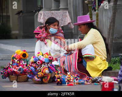 Le donne indigene, seduti a terra, vendono prodotti ai passanti a Miraflores, uno dei quartieri più esclusivi della città di Lima Foto Stock