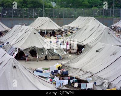 Centro di detenzione vietnamita di Shek Kong, eretto in poche settimane nel 1989 all'estremità occidentale della pista militare di Shek Kong, New Territories, Hong Kong. Le tende sono state erette sulla pista e l'erba su entrambi i lati, circondata da una recinzione in lamiera, sormontata da filo spinato. Decine di migliaia di richiedenti asilo vietnamiti sono passati attraverso il campo negli anni di attività. Foto scattata nel Dicembre 1990. Foto Stock