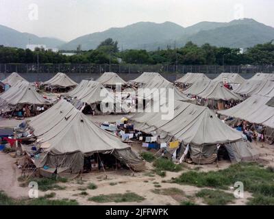 Centro di detenzione vietnamita di Shek Kong, eretto in poche settimane nel 1989 all'estremità occidentale della pista militare di Shek Kong, New Territories, Hong Kong. Le tende sono state erette sulla pista e l'erba su entrambi i lati, circondata da una recinzione in lamiera, sormontata da filo spinato. Decine di migliaia di richiedenti asilo vietnamiti sono passati attraverso il campo negli anni di attività. Foto scattata nel Dicembre 1990. Foto Stock