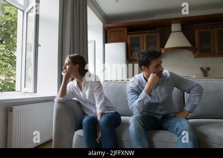 Triste giovane coppia si siede a parte sul divano dopo litigare Foto Stock