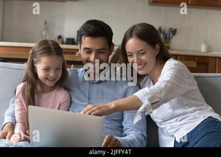 Coppia e figlia trascorrono il fine settimana a casa utilizzando un computer portatile Foto Stock