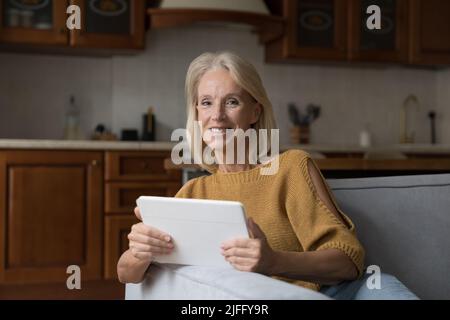 Donna anziana di buona qualità che usa il tablet digitale a casa Foto Stock