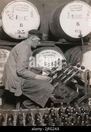 Storia del vino alla fine del 19th-20th secolo. L'immagine mostra un uomo che lavora presso la società mercantile del vino J. Cederlunds Söner in Svezia, spillando Punsch dalle botti in bottiglie. La bevanda alcolica Punsch si riferisce ad un tipo specifico di liquore alcolico e punch popolare in Svezia. È più spesso descritto come punsch svedese. È prodotto dalla miscelazione di arak liquori, brandy o rum con tè arrak, zucchero e acqua ed è stato portato per la prima volta in Svezia da Giava nel 1733. Il Punsch ha solitamente alcool al 25% in volume. È ubriaco sia riscaldato che freddo. Alcuni credono alla parola punch/punsch cam Foto Stock