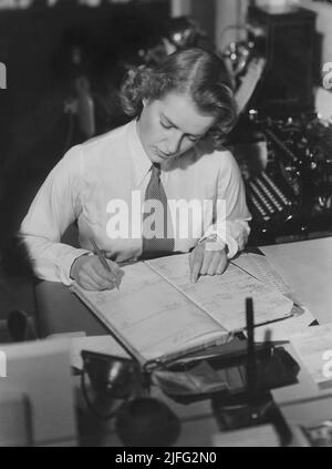 1940s addetto all ufficio. Una giovane donna in un ufficio dove lei a rendere note di attenzione in un registrer. Ella è vestito con una camicia bianca e una cravatta. La Svezia 1940s Foto Stock