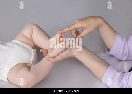 Primo piano, le mani della madre toccano le punte piccole del neonato Foto Stock