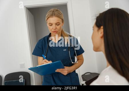 Il medico compila il modulo di rapporto medico sulle cure mediche dei pazienti durante l'appuntamento Foto Stock