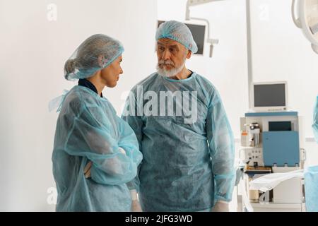 Due medici chirurghi stanno conferendo nella sala operatoria prima dell'intervento chirurgico Foto Stock