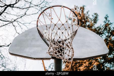 Un tiro ad angolo basso di un vecchio cerchio da basket in un parco Foto Stock
