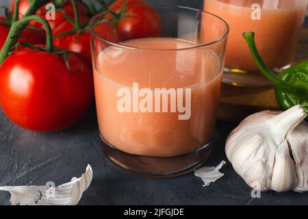 Primo piano della tipica zuppa spagnola di pomodoro (gazpacho andaluso) con pomodori freschi, peperoni verdi, aglio e olio d'oliva. Bicchiere di delizioso gazpacho. Foto Stock