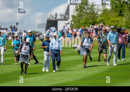 Il gruppo leader si dirige verso il fairway dalla 1st tee durante il loro ultimo round al LIV Golf Invitational London al Centurion Club Foto Stock