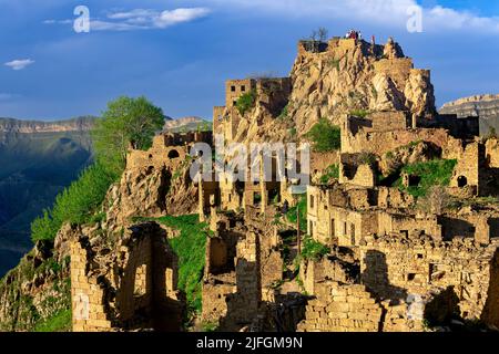 Gamsutl, Russia - 15 maggio 2022: Vista del villaggio abbandonato sulla cima di una montagna in Dagestan, con i turisti tra le rovine Foto Stock