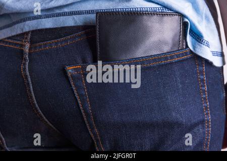 Vista ravvicinata del portafoglio in pelle marrone nella tasca posteriore dei jeans. Foto Stock