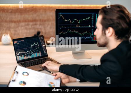 Smart focalizzato caucasico maschio trader investitore, analizzando criptovaluta mercato finanziario, guarda i grafici, elaborare una strategia criptata, analizzare i rischi. Investimenti, negoziazione in borsa Foto Stock