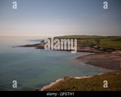 Una vista aerea del mare circondato da verdi colline sotto il cielo blu luminoso Foto Stock