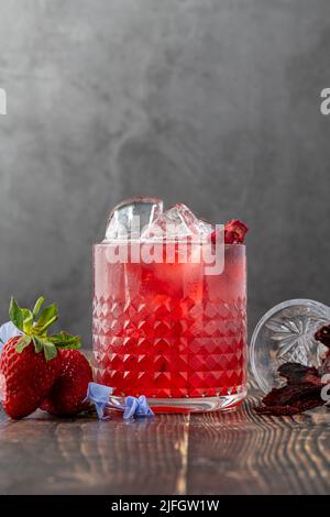 Tè freddo alla fragola ghiacciato con fette di fragole secche su un tavolo di legno Foto Stock