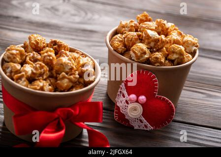 Secchielli in cartone con popcorn caramellato e decorazioni valentine su fondo da cucina Foto Stock