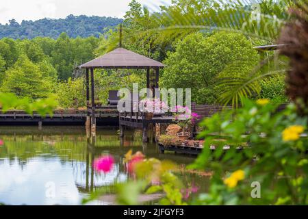 Gazebo in legno con lettini per rilassarsi su una terrazza con fiori accanto ad un lago sull'isola tropicale della Thailandia. Natura e concetto di viaggio Foto Stock