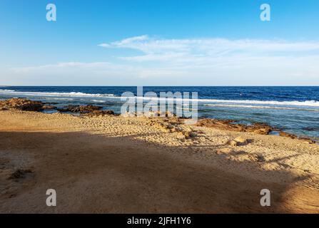 Spiaggia di sabbia e bella stagcape del Mar Rosso vicino a Marsa Alam, Egitto, Africa. Le onde si infrangono sulla barriera corallina e sulla scogliera. Foto Stock