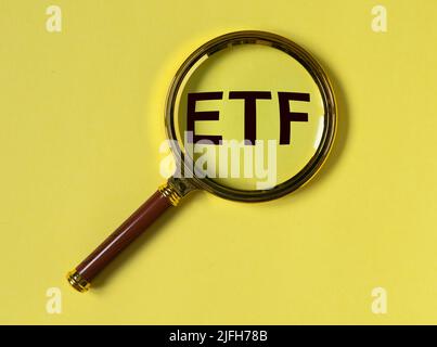 Acronimo ETF tramite lente di ingrandimento su sfondo giallo. Foto di alta qualità Foto Stock