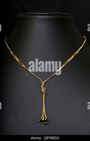 mangalsutra a catena in oro fantasia con perle nere e nodo fantasia su sfondo nero Foto Stock