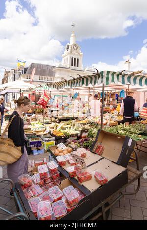 Donna mercato dello shopping UK; donna caucasica di 20s anni che acquista frutta in una bancarella di frutta, Saffron Walden mercato quadrato, Saffron Walden, Essex Inghilterra Regno Unito Foto Stock