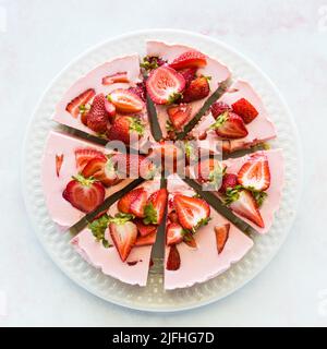 Una cheesecake alla fragola a fette, presa dall'alto. Foto Stock