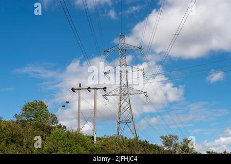 Elettricità tralicci contro un cielo blu Foto Stock