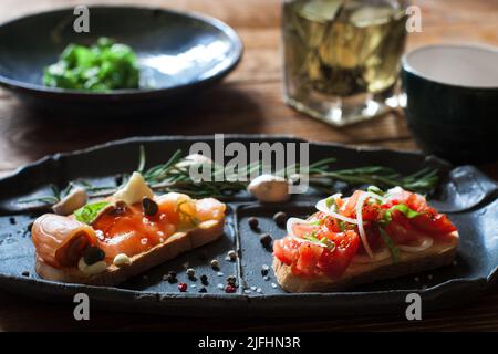 Sandwich con salmone e piatto nero di pomodoro Foto Stock