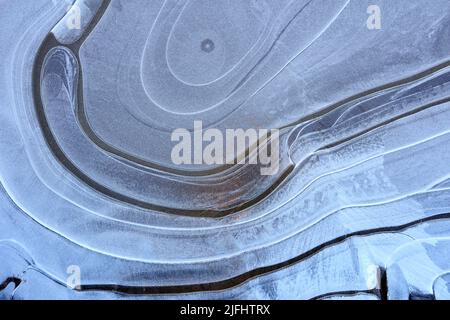 Sulla superficie della pozzanghera ghiacciata, modello di linee curve. Foto Stock