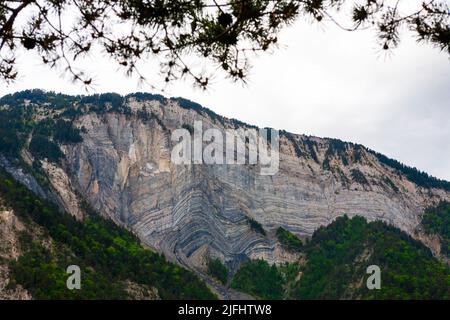 Rocce sedimentarie distorte nella scogliera che domina la città di le Bourg-d'Oisans, Isère dipartimento nel sud-est della Francia Foto Stock