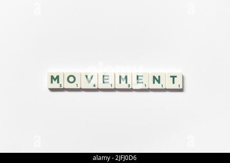 Movimento formato da piastrelle scrabble su sfondo bianco. Foto Stock