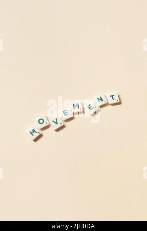 Movimento formato da blocchi scrabble su sfondo beige. Foto Stock