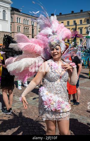 Interprete che indossa un costume rosa in piuma che si prepara per la sfilata navale Helsinki Samba in Piazza del Senato, Helsinki, Finlandia Foto Stock