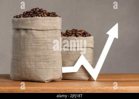 Un sacchetto di chicchi di caffè e una freccia rivolta verso l'alto. Il costo del caffè nei mercati del mondo. Il concetto di crescita del costo del caffè Foto Stock